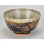 JIM MALONE (born 1946); a stoneware bowl covered in tenmoku breaking to kaki glaze with green ash
