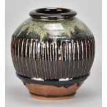 MIKE DODD (born 1943); a large part fluted stoneware jar partially covered in tenmoku breaking to