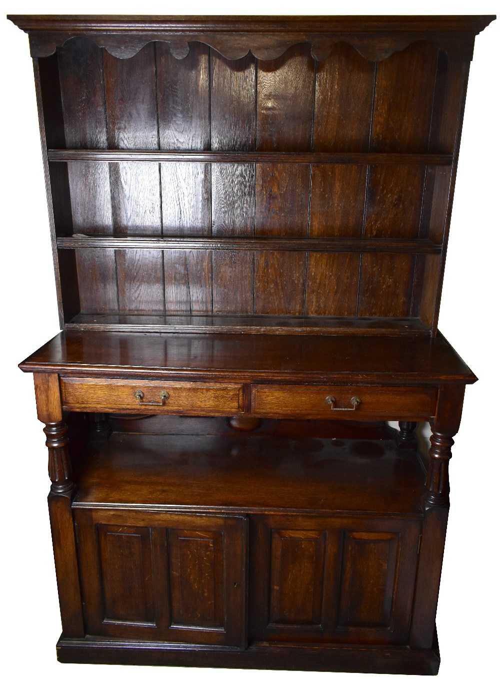 An Edwardian oak buffet, with associated plate rack top, above two drawers and two cupboard doors,