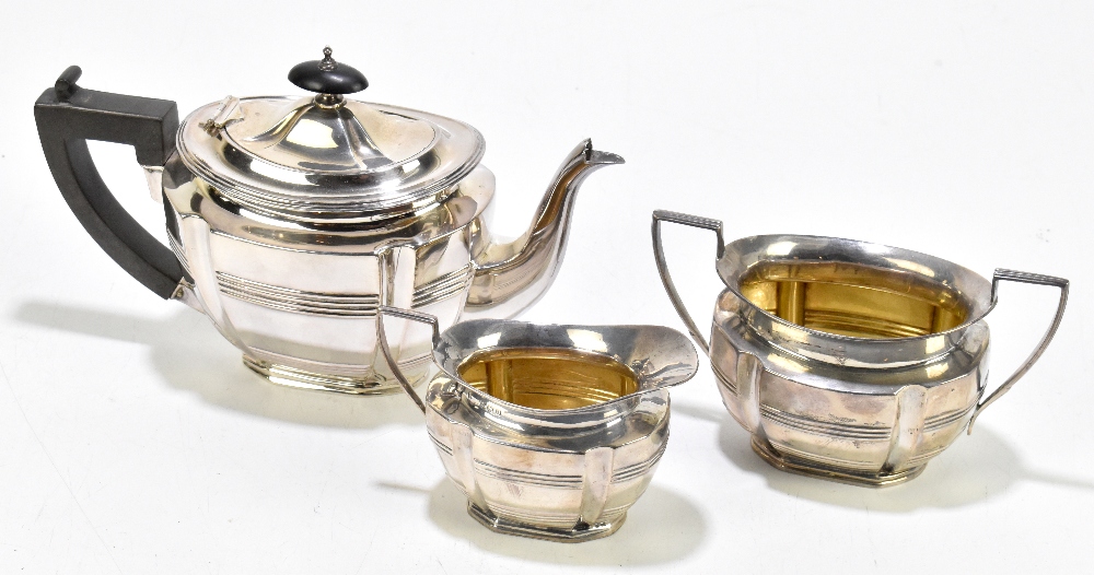 A George V hallmarked silver three piece bachelor's tea service, the teapot with ebonised finial and