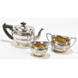 A George V hallmarked silver three piece bachelor's tea service, the teapot with ebonised finial and