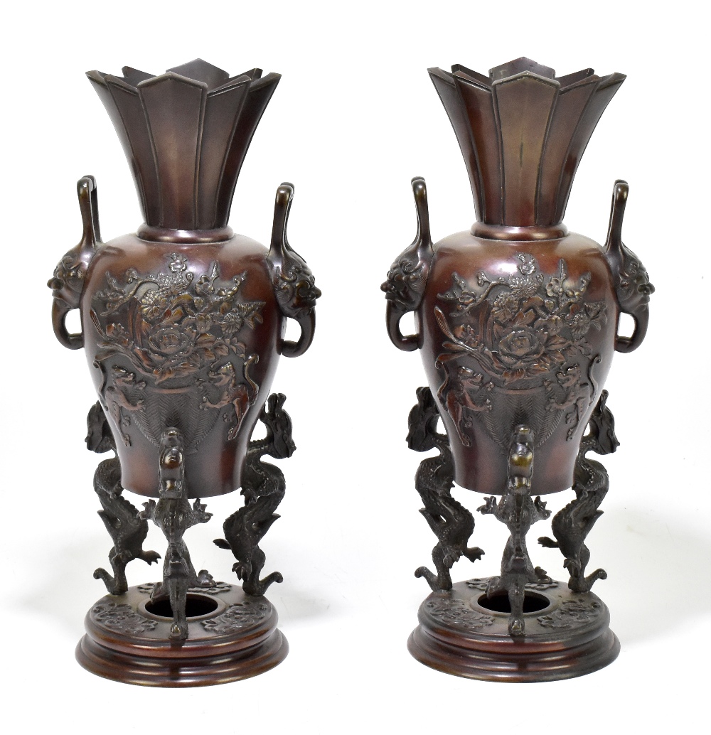 A pair of Japanese Meiji Period bronze koros with applied mask head handles and floral sprays,