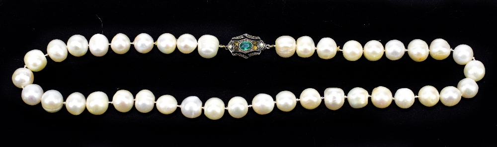 An Art Deco design hand tied string of pearls, the white metal clasp set with emerald and citrine,