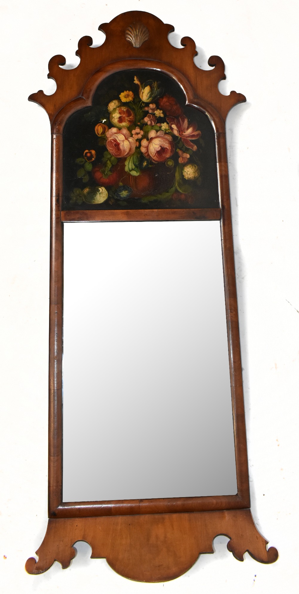 A Georgian style walnut framed wall mirror with carved inset panel, oil, still life, length 110cm.