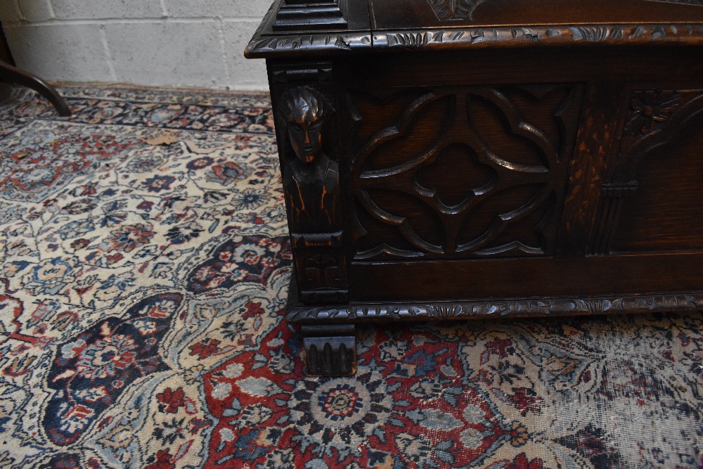 A 1920s carved oak monk's bench with carved and panelled back above the hinged seat, width 107cm, - Image 7 of 7