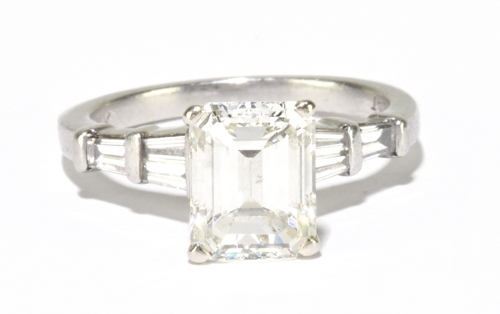 A platinum and diamond solitaire ring, the principal emerald step cut stone, weighing 3.04cts,