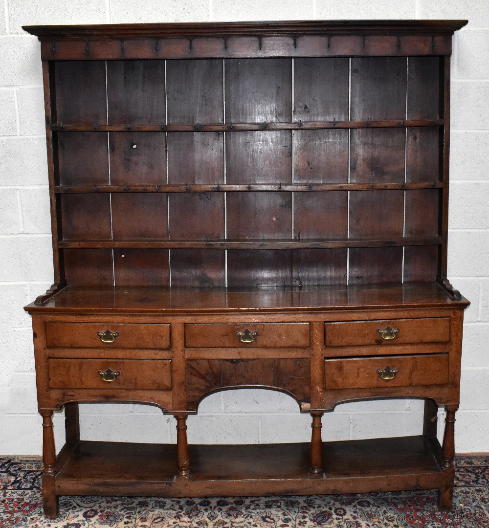 An 18th century oak dresser with boarded plate rack back with five drawers raised on block feet,