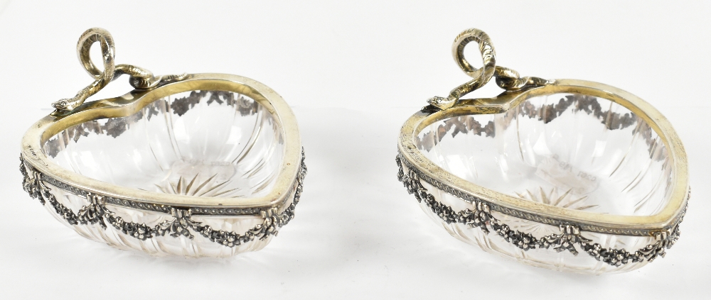 An unusual pair of 800 grade silver mounted and cut glass heart shaped bowls, with serpent raised