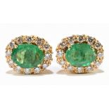 A pair of yellow metal emerald and diamond cluster ear studs with butterfly backs, the oval