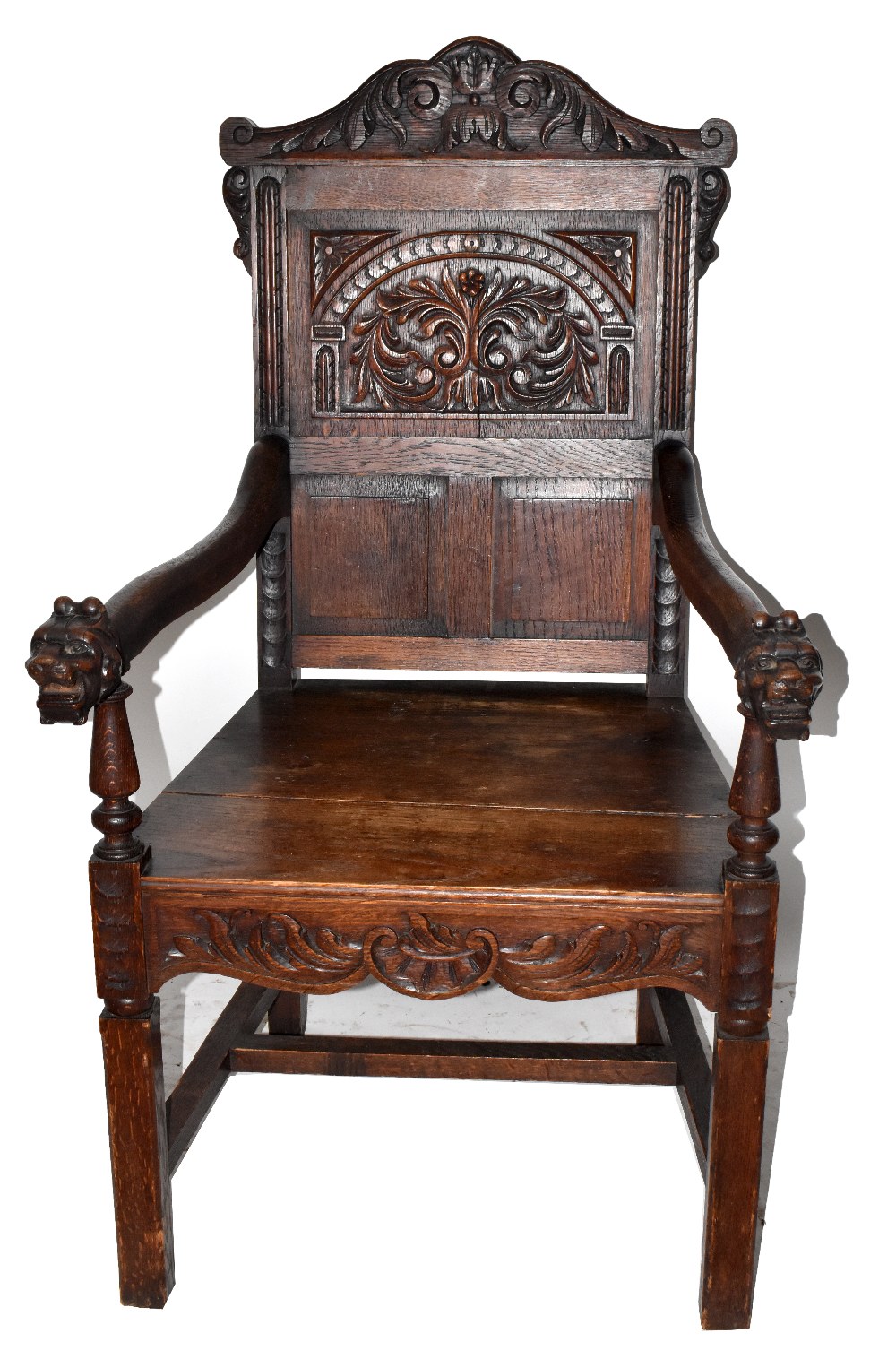 A Victorian carved oak open arm elbow chair with iron mask terminals and square supports.