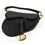 A black leather saddle shaped handbag with front flap with magnetic D-stirrup with gold tone