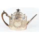 A George III hallmarked silver oval teapot, with embossed floral and scroll detailing, carved wood