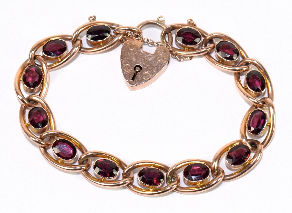 An early 20th century 9ct rose gold and garnet set open work bracelet with padlock clasp, length