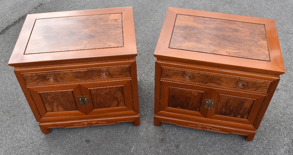 A pair of modern Chinese carved hardwood bedside cabinets, with one drawer and two cupboard doors,