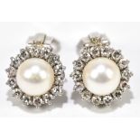 A pair of white metal diamond and cultured pearl ear clips, each set with fourteen diamonds, centred