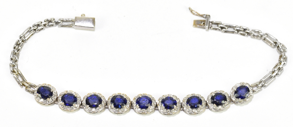 A diamond and blue stone white metal bracelet, set with nine oval stones within a serpentine oval