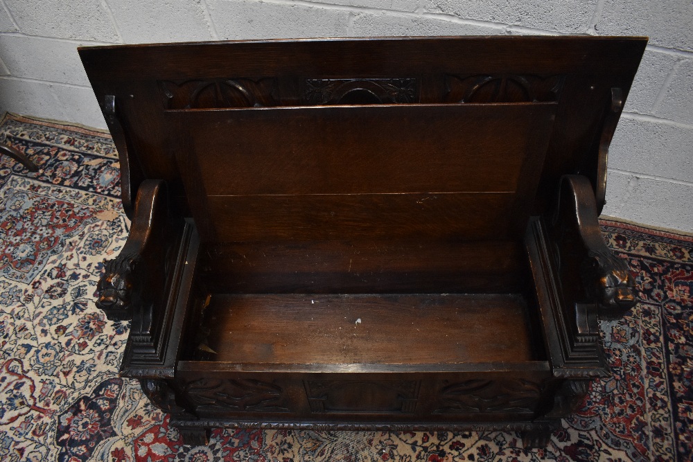 A 1920s carved oak monk's bench with carved and panelled back above the hinged seat, width 107cm, - Image 5 of 7