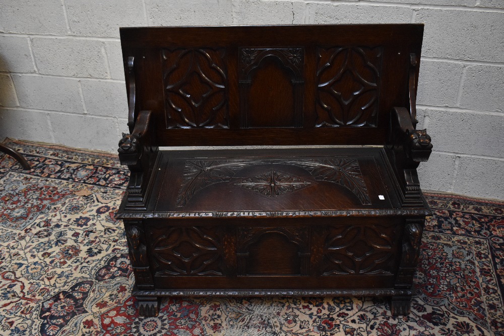 A 1920s carved oak monk's bench with carved and panelled back above the hinged seat, width 107cm, - Image 4 of 7