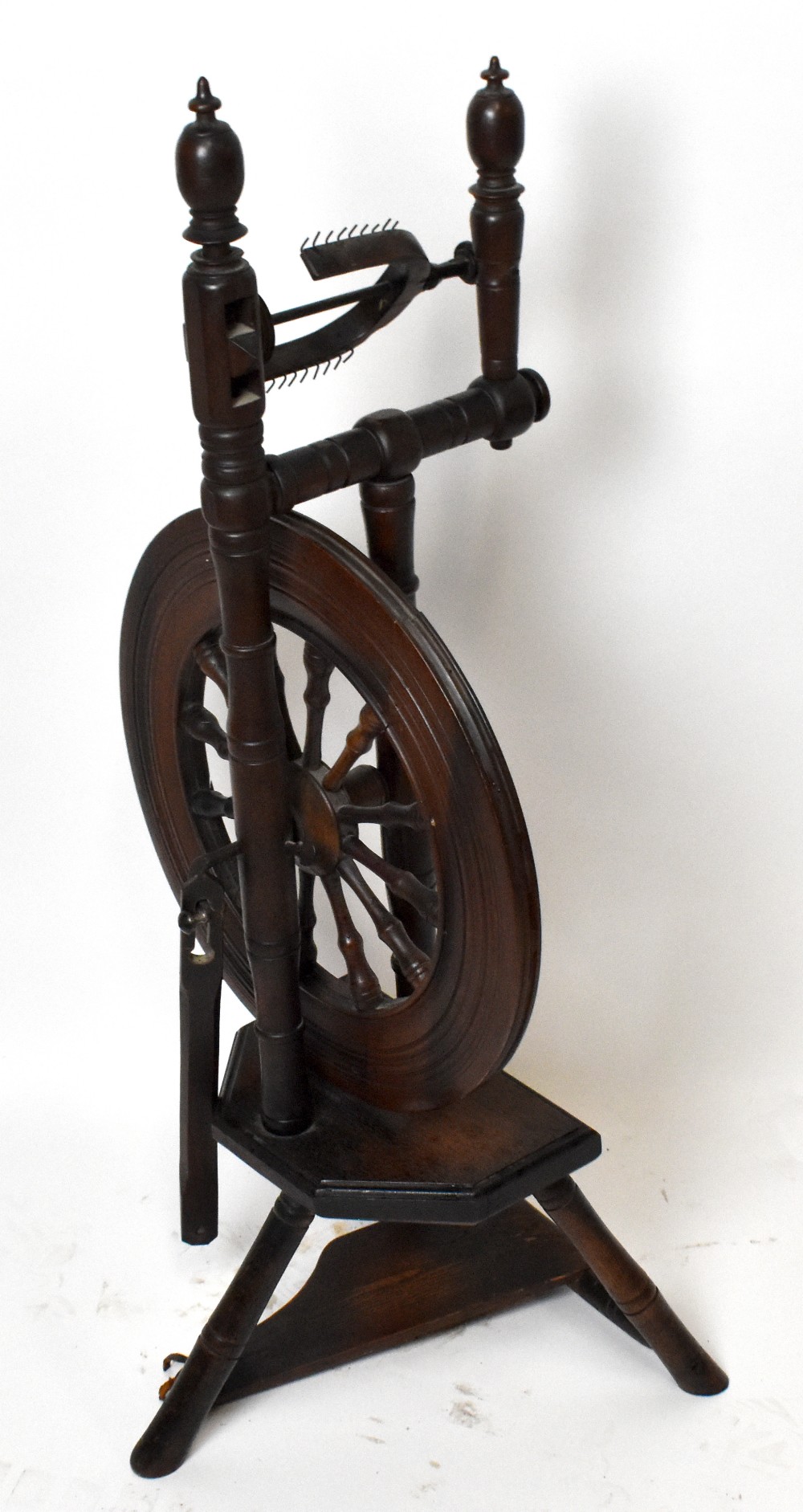 An early 19th century stained pine and oak spinning wheel, height 90cm.