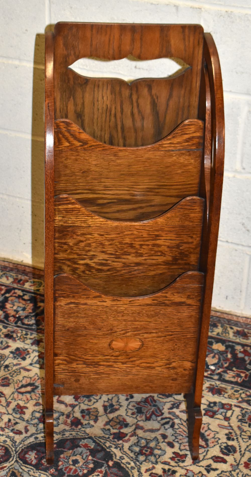 An Arts & Crafts inlaid oak freestanding three division magazine rack, with carved back panel,