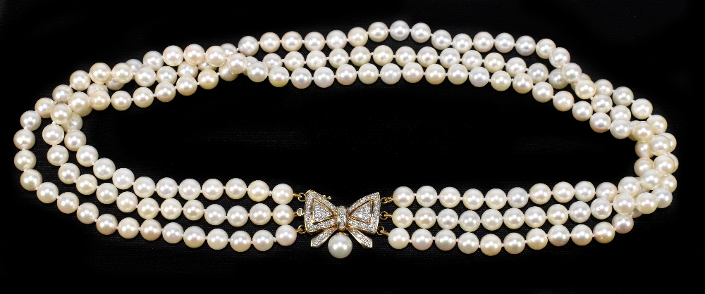 A three row Akoya pearl choker, with a yellow metal diamond set bow clasp, surmounting a single