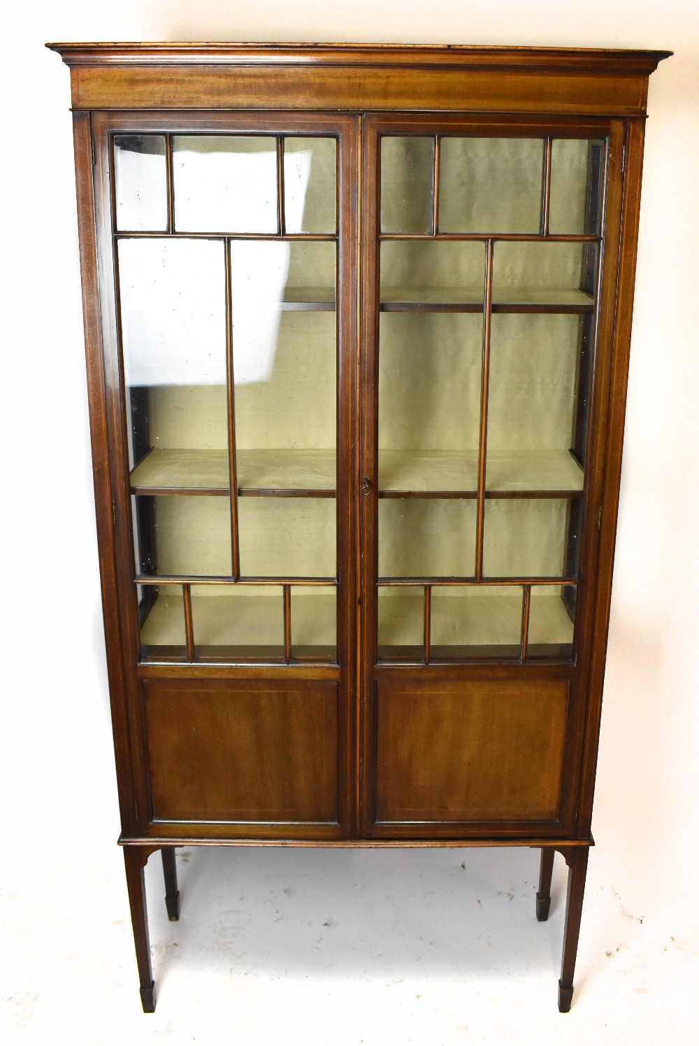 An Edwardian line inlaid mahogany display cabinet, with two glazed and panelled doors, enclosing