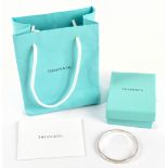 TIFFANY & CO; a sterling silver round bead edged bangle, with Tiffany & Co 250 inscribed to the
