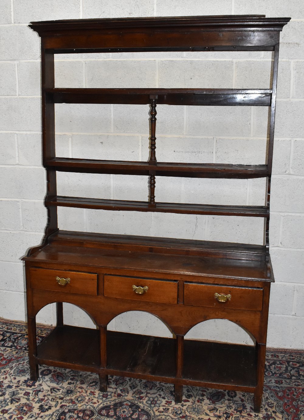 An 18th century oak dresser, with open plate rack back having central turned spindles and three