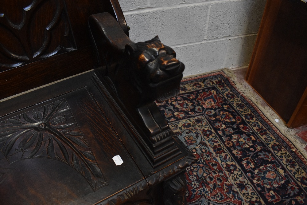 A 1920s carved oak monk's bench with carved and panelled back above the hinged seat, width 107cm, - Image 6 of 7