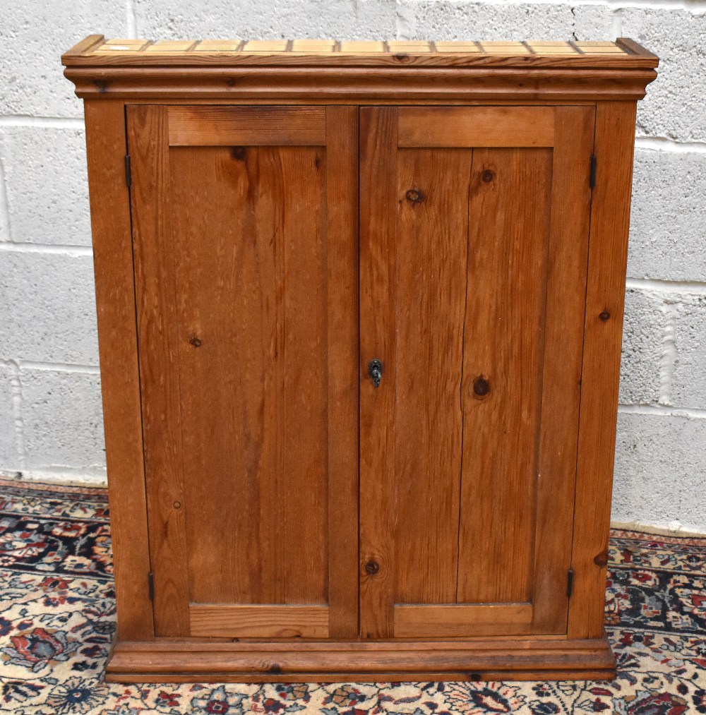 A pine two door cupboard, with tiled top enclosing one fixed shelf, height 89cm, width 69.5cm, depth