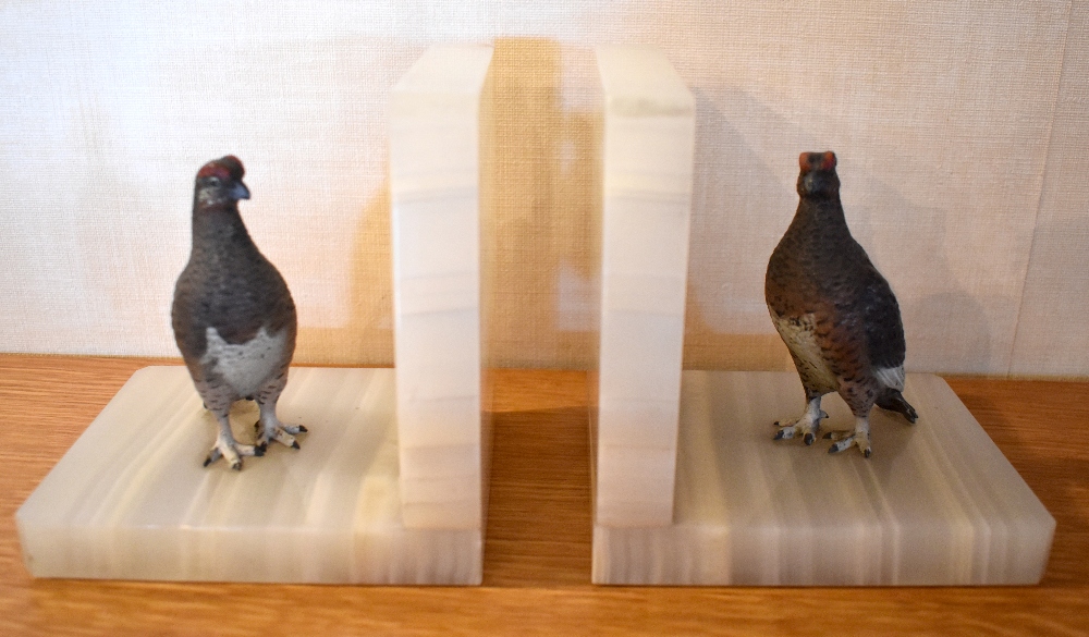 A pair of 1930s Austrian cold painted figures of grouse mounted on polished white onyx bookends,