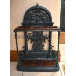 A large Victorian cast iron stick stand with pierced scrolling fruit decorated arched back, mahogany