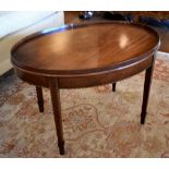 An Edwardian oval mahogany coffee table with raised gallery, chevron string inlay to the frieze