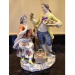 An early 20th century Meissen porcelain figure group of a man holding a basket of flowers beside a