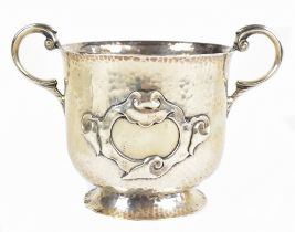 A late Victorian hallmarked beaten silver Arts & Crafts twin handled cup, with stylised central