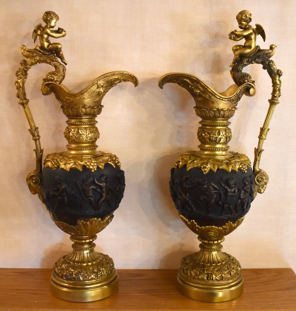 A large pair of decorative 20th century bronze ewers, each with cherub surmount above the