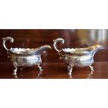 HENRY BRIND; a pair of George II hallmarked silver and later decorated sauce boats, each with high