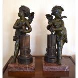 A pair of late 19th century bronze figures of cherubs, each standing before a fluted column and