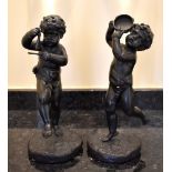 A pair of early 20th century bronze figures of cherubs, one playing the triangle, the other a