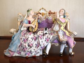 A Meissen Marcolini period porcelain group of a couple seated on an elaborate settee, playing