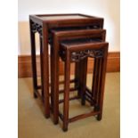 A Chinese nest of three hardwood occasional tables with pierced friezes, raised on square