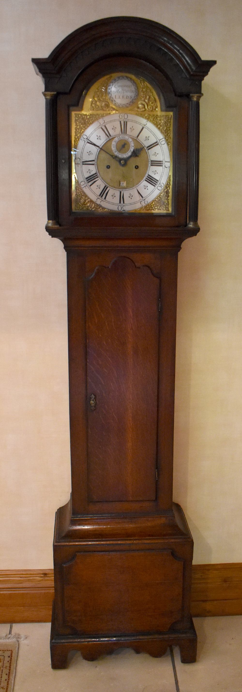 A George III oak longcase clock, the arched hood and dial with Roman numerals to the silvered