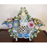 A mid/late 19th century floral encrusted porcelain basket with fixed handle and hand painted