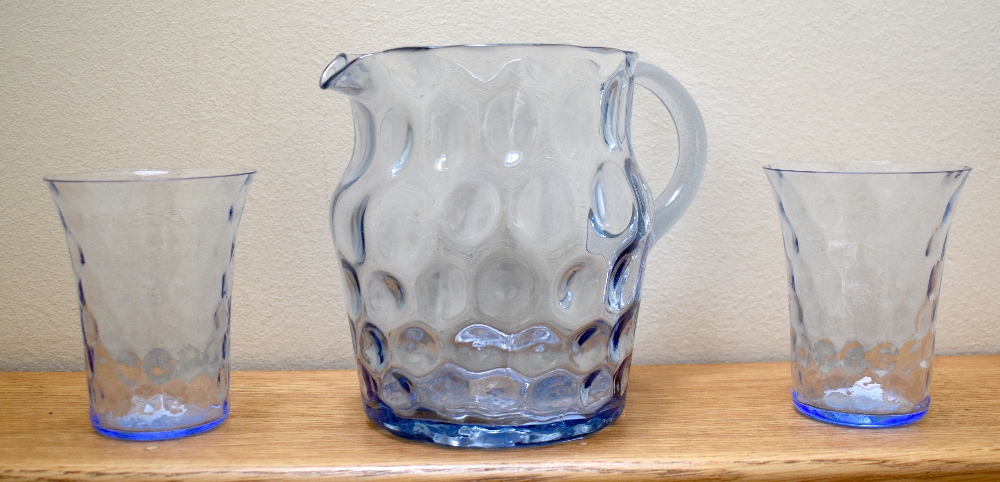 An Edwardian dimpled pale blue glass water jug, height 15.75cm and a pair of matching beakers (3).