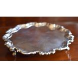 A George III Irish hallmarked silver waiter with shaped rim, raised on three stepped hoof