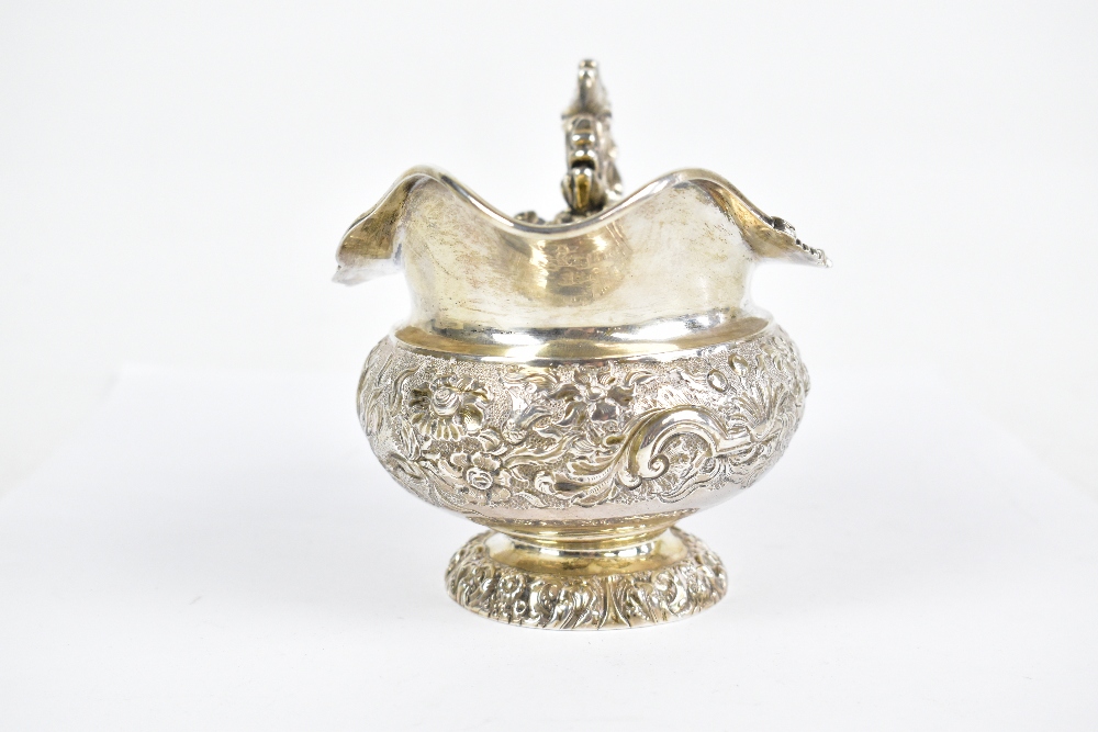 A George IV hallmarked silver cream jug with ornate scroll handle and embossed main body decorated - Bild 2 aus 6