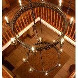 An enormous bespoke hand wrought three tiered ceiling light, each tier set with candle bulbs and