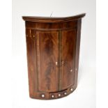 A 19th century flame mahogany inlaid wall-hanging corner cabinet,