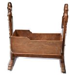 A 19th century pine swinging crib with Gothic inspired side supports and base united with