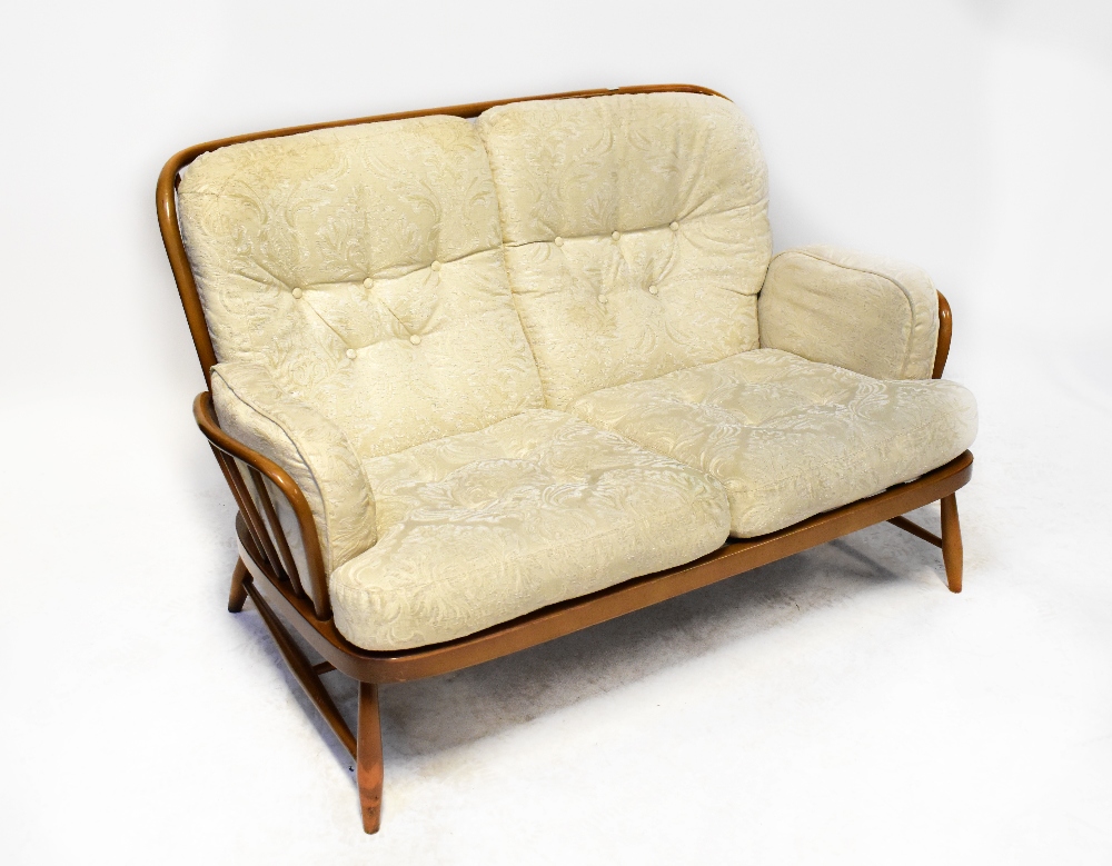 ERCOL; a Jubilee two-seater stick back settee, raised on turned cross-stretchered supports.